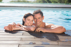 Portrait of a smiling young couple in swimming pool on a sunny day